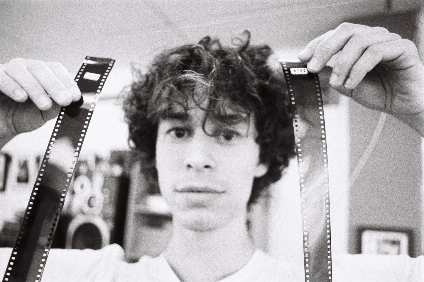 Sample shot: man holding up two strips of developed 35mm film either side of his head