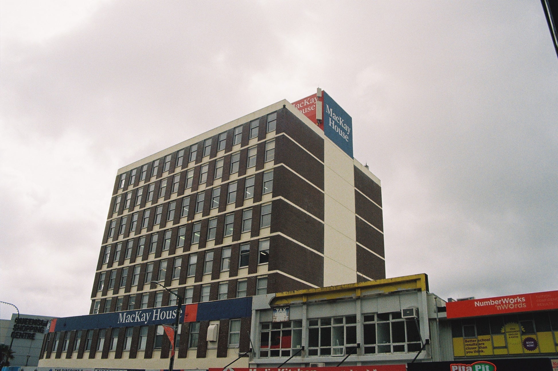 Tall building with multiple signs on a cloudy day