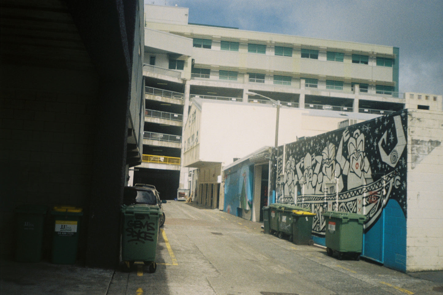 Street scene with a mural on a building wall and parked cars.