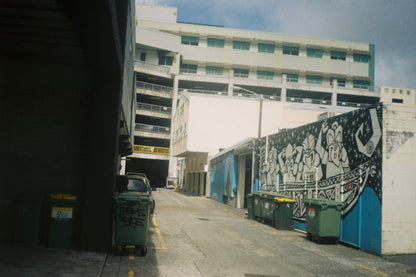 Street scene with a mural on a building wall and parked cars.