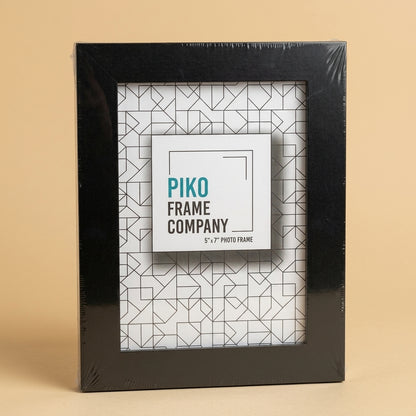 Black PIKO 5x7 frame in shrink wrap with printed insert card, on a beige background