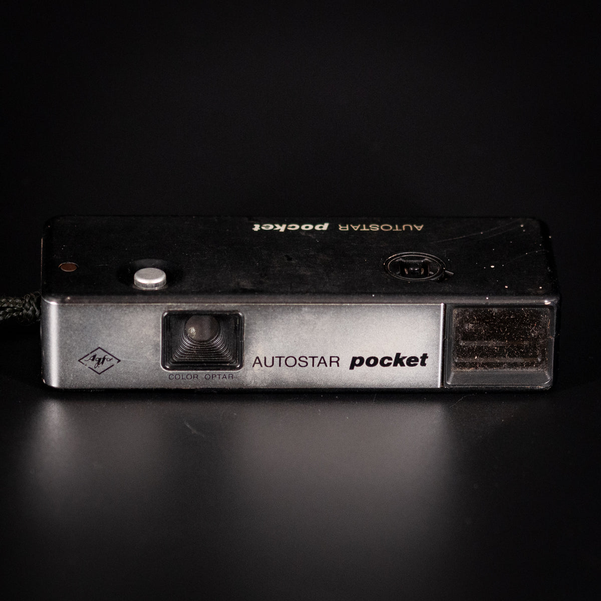 Agfa Autostar Pocket camera front on, silver and black body on a dark background