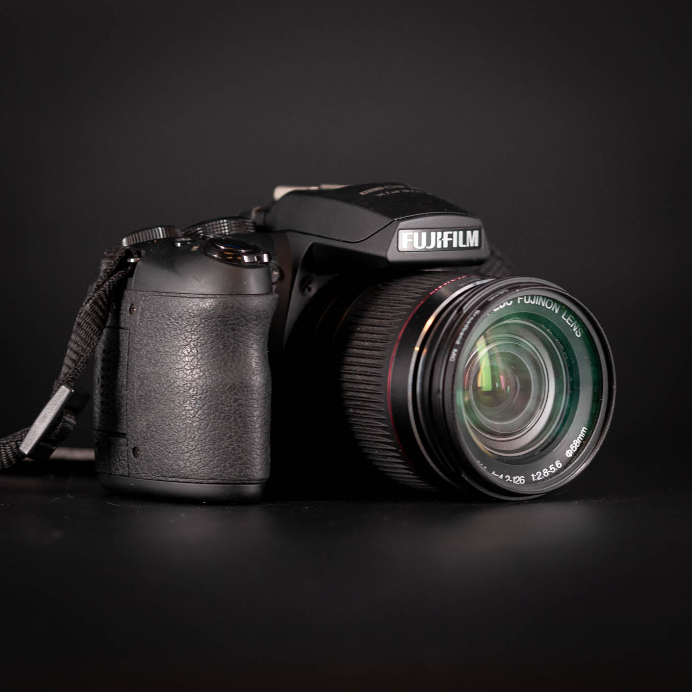 Fujifilm Digital camera with lens cap on a black background