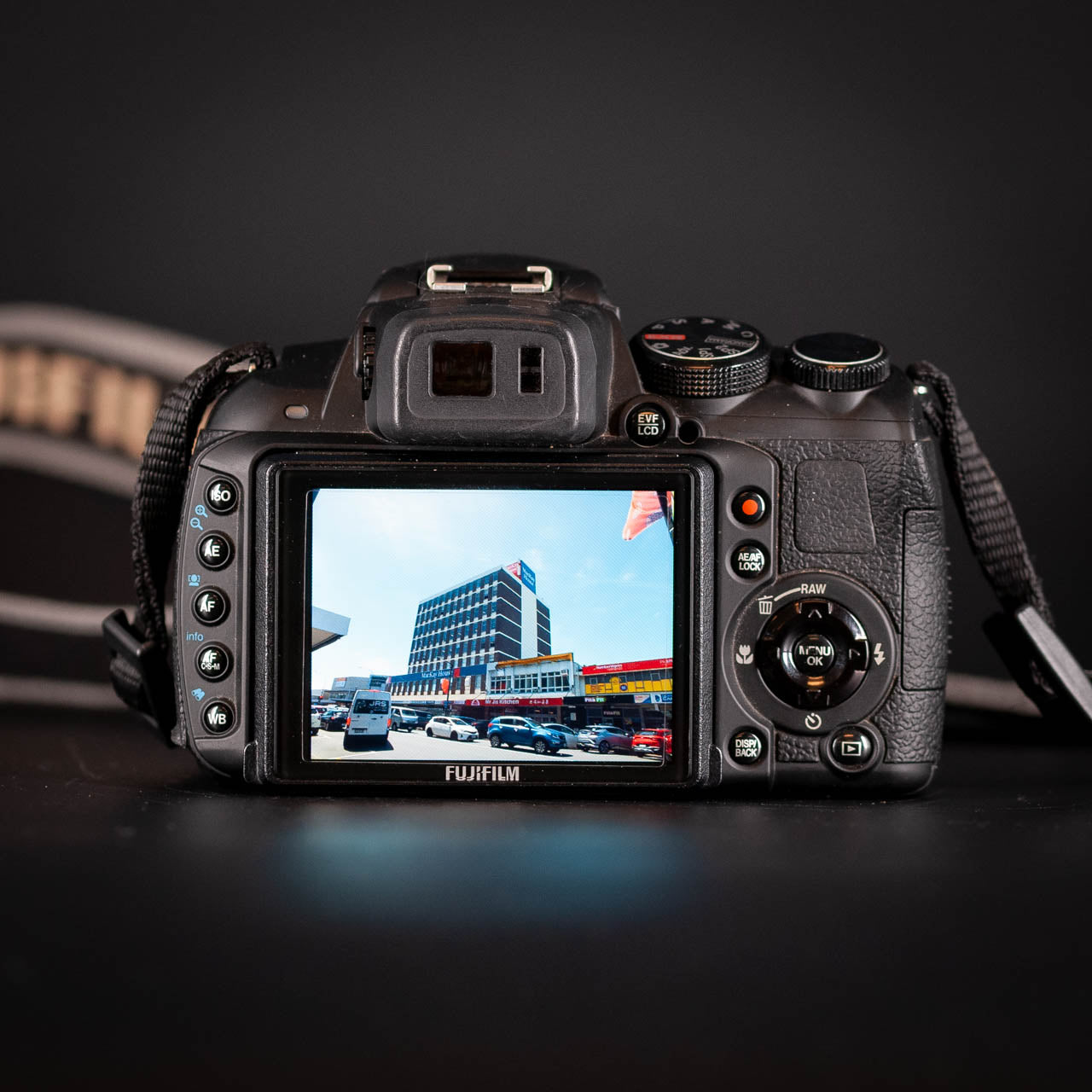 Fujifilm camera with screen displaying a cityscape on a dark background