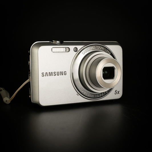 Front of the silver Samsung ES80 compact camera with 5x zoom lens, on black