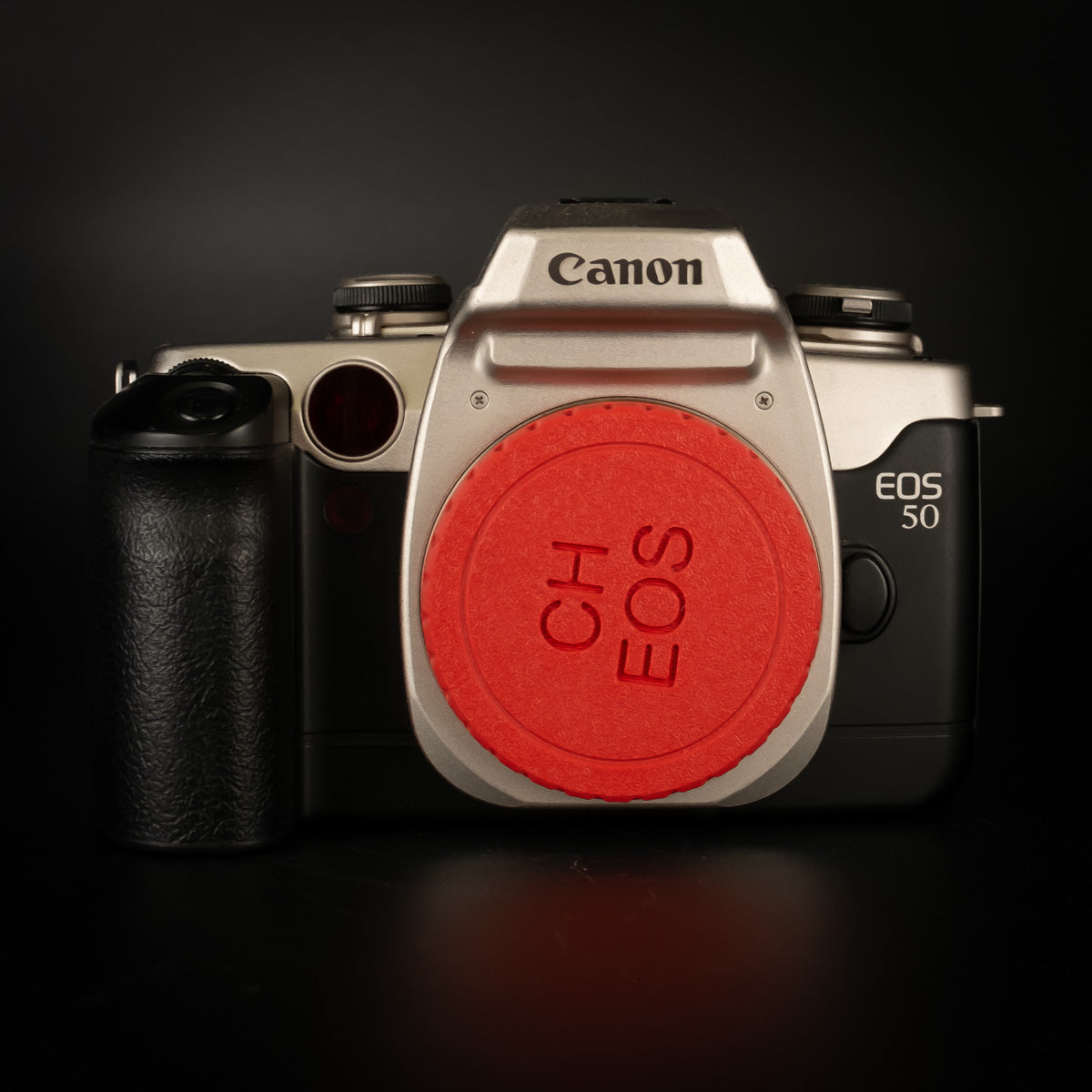 Canon EOS 50 silver and black film SLR body with a red body cap fitted