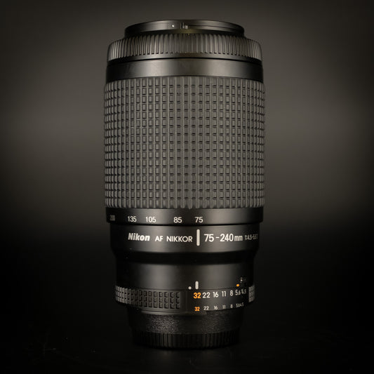 Nikon AF Nikkor 75-240mm f/4.5-5.6D zoom lens standing upright on a dark background