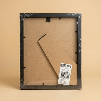 Back of the black 8x10 frame in shrink wrap, showing MDF backing, clips and barcode label