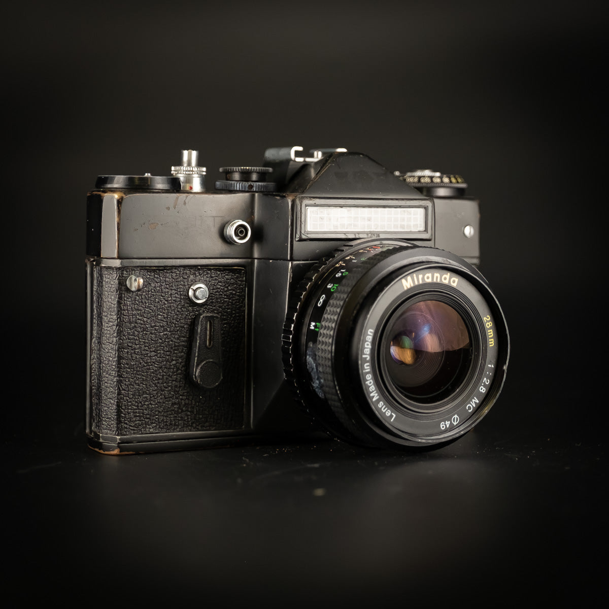 Black Zenit-EM camera with Miranda 28mm f/2.8 lens, front three-quarter view on dark background