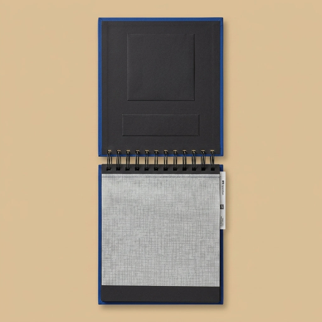 Hama spiral album opened flat, showing black pages and interleaving sheet, on a beige background