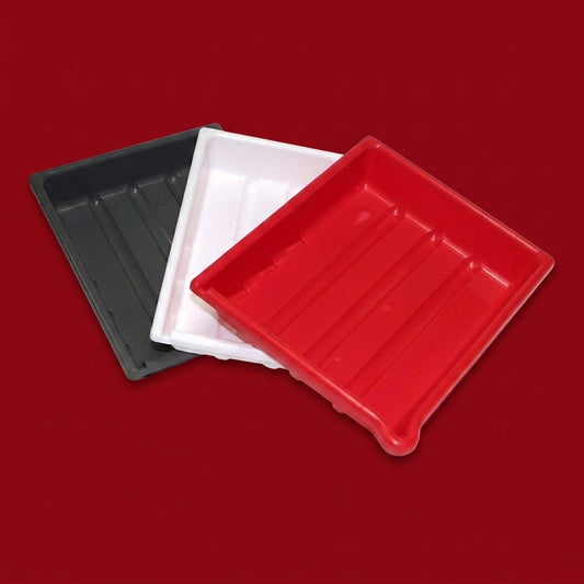 Three Paterson 10x12 developing trays in black, white and red, fanned out on a dark red background