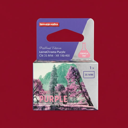 Boxed LomoChrome Purple 35mm film, purple and pink packaging on a dark red background
