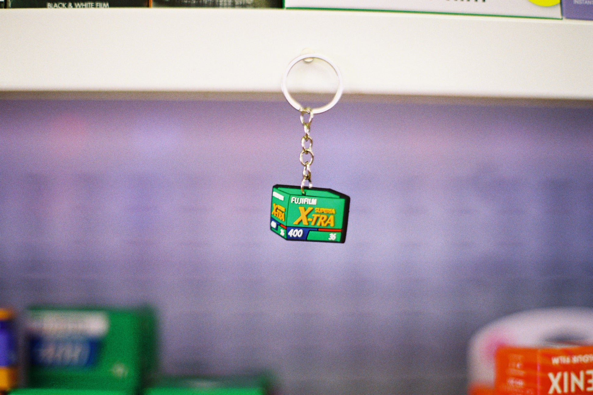 Keychain shaped like a roll of Xtra film on a blurred background